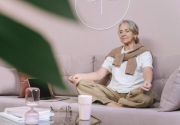 Kobieta siedząca w medytacyjnej pozycji na kanapie, relaksująca się w spokojnym otoczeniu