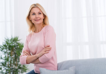 Rozmyślona kobieta w okresie menopauzy ubrana w różowy sweter