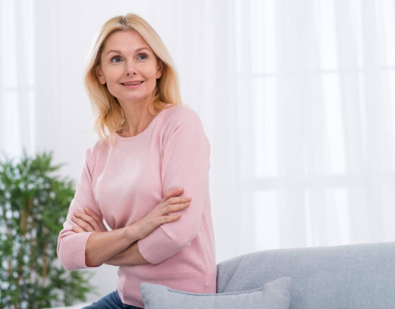 Rozmyślona kobieta w okresie menopauzy ubrana w różowy sweter